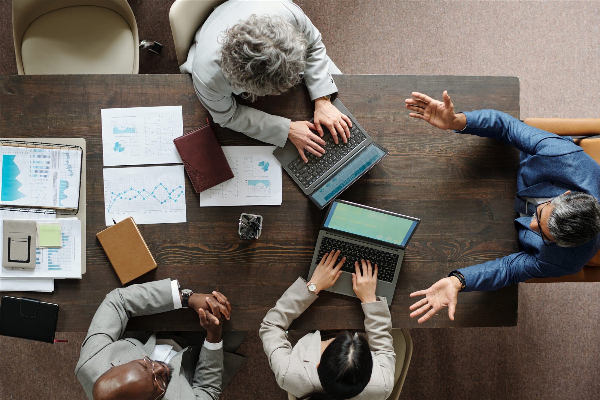 Diverse business team collaborating around laptops and performance data